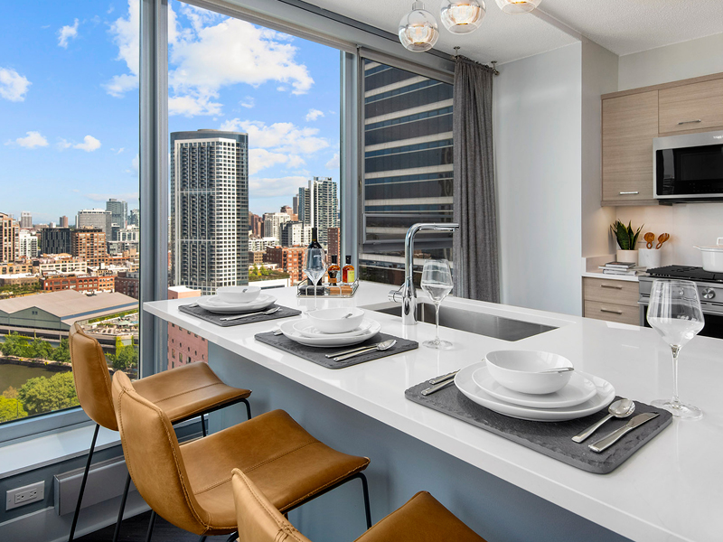 Residence kitchen with white quartz counters, kitchen island, European flat panel cabinets, and views of downtown Chicago